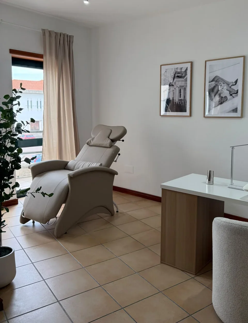 Sala da NUA: uma cadeira de tratamento, a janela com cortinados e dois quadros na parede
